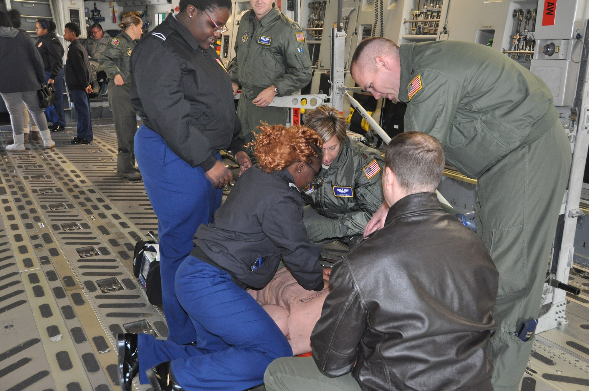 Airmen from the 445th Aeromedical Evacuation Squadron show two Meadowdale High School students how to do chest compressions on a simulated patient onboard a 445th Airlift Wing C-17 Globemaster III Oct. 18, 2018.