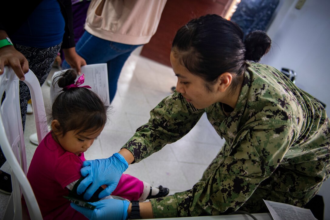 Hospitalman Macky Refugia, from Guam, checks the vitals of a patient at one of two medical sites.