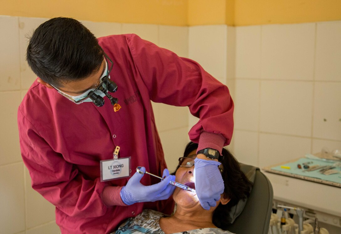 Lt. True Xiong, a dentist from Spokane, Wash., prepares a patient for surgery at one of two medical sites.