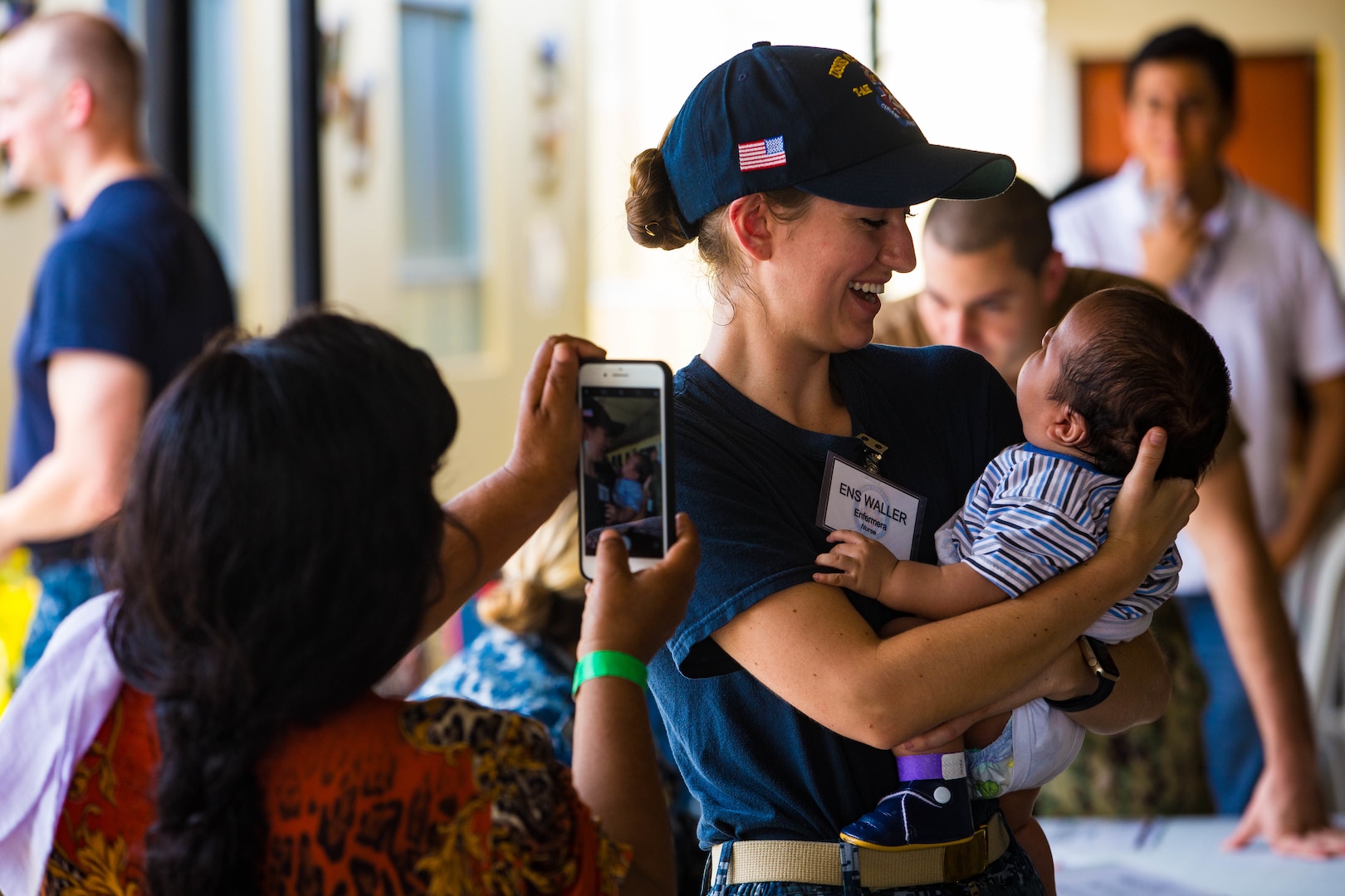 Ens. Abigail Waller, from Mystic, Conn., holds the baby of a patient at one of two medical sites.