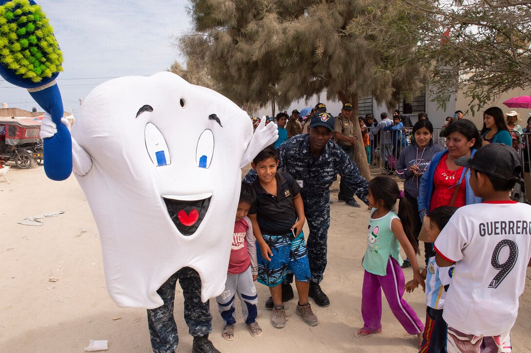 Chief Hospital Corpsman Orlando Alencia, from Miami, wears a tooth mascot while entertaining children to promote good dental hygiene at one of two medical sites.