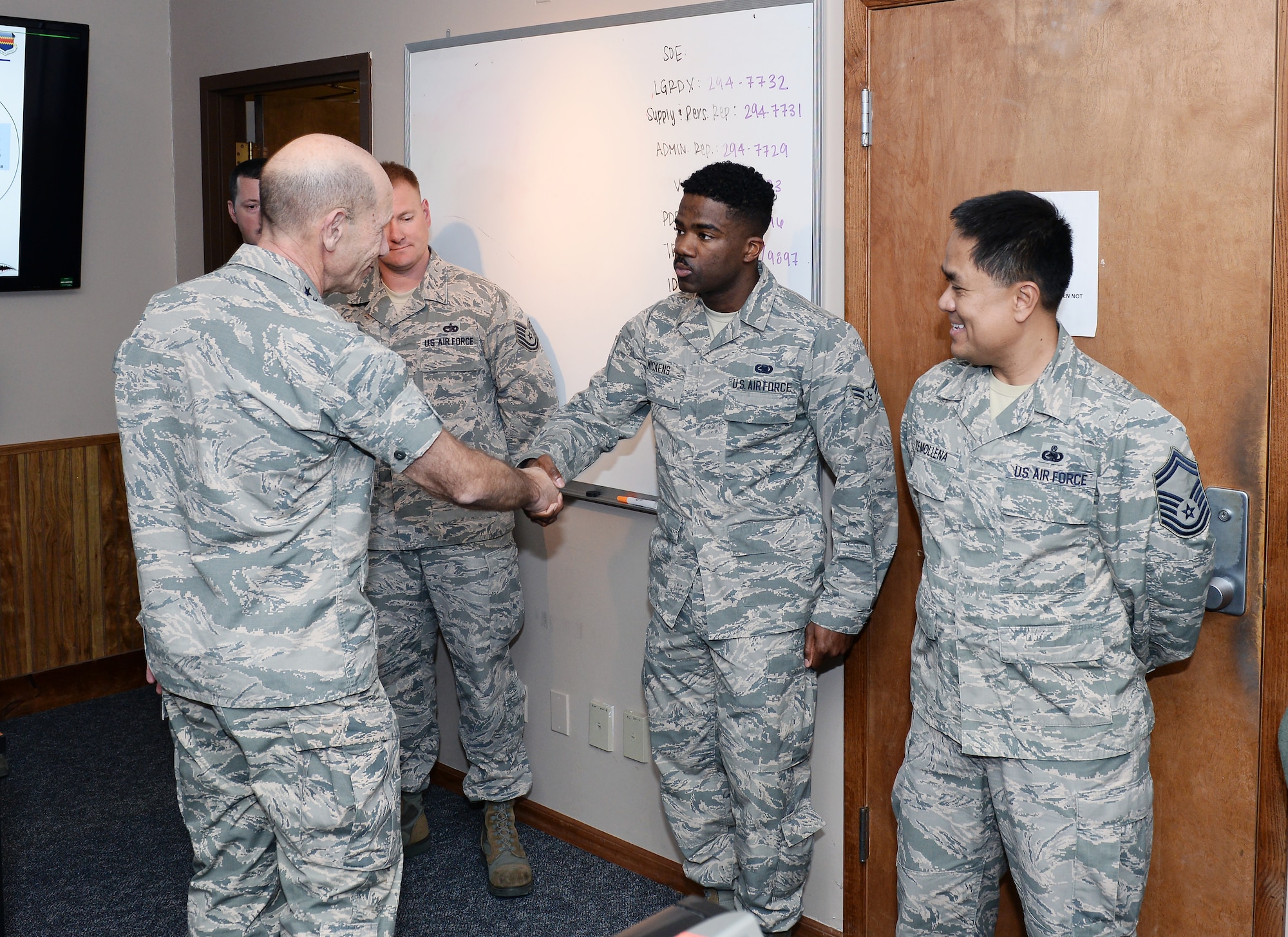 U.S. Air Force Gen. Mike Holmes, the commander of Air Combat Command, coins Airman 1st Class Devonte Mickens, a 55th Logistics Readiness Squadron materials handler, Oct. 30, 2018, inside the installation deployment readiness cell at Offutt Air Force Base, Nebraska.