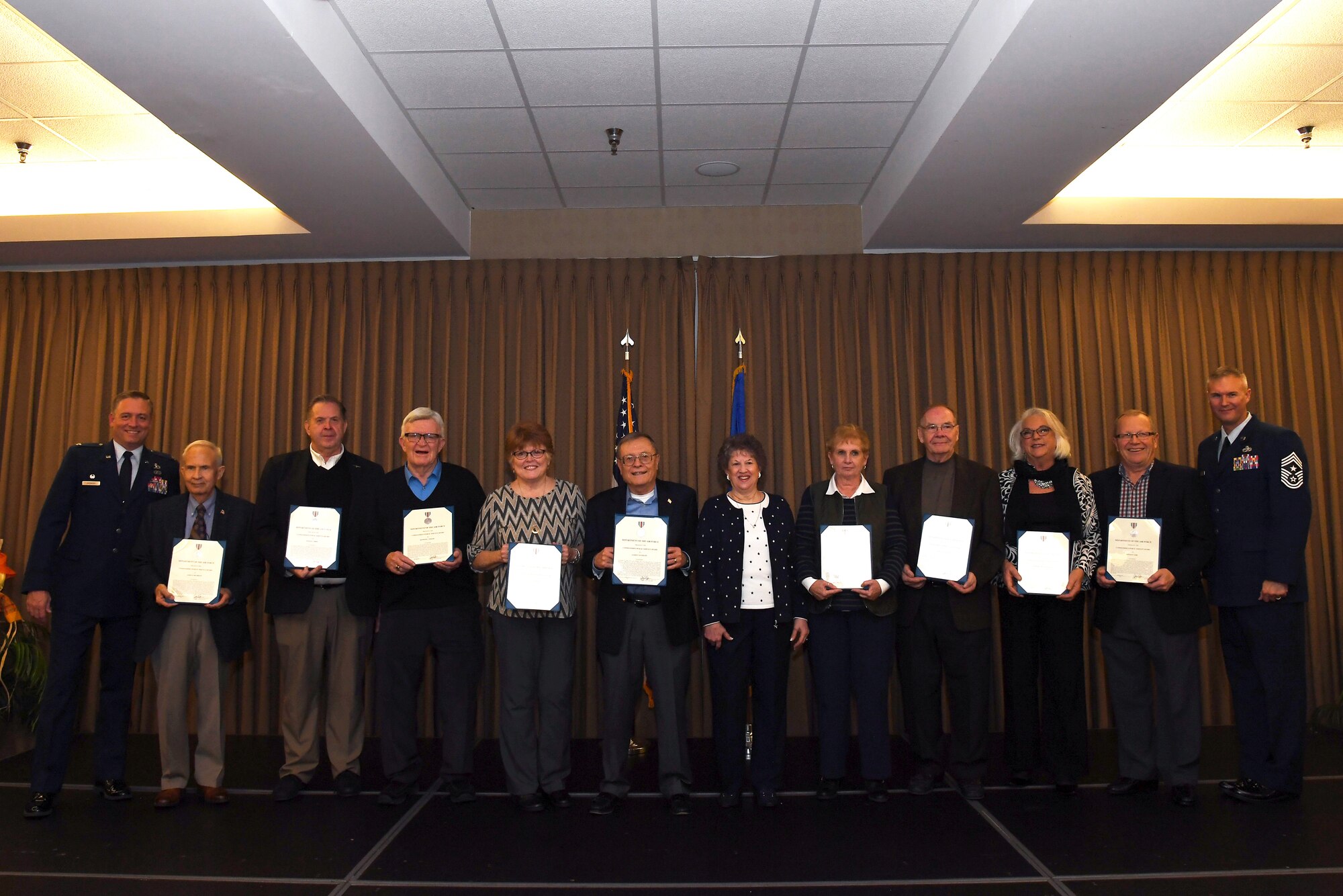 Local military ambassadors stand for a photo beside Col. Benjamin Spencer, 319th Air Base Wing commander, left, and Chief Master Sgt. Brian Thomas, 319 ABW command chief, following an appreciation ceremony October 26, 2018, on Grand Forks Air Force Base, North Dakota. Each of the ambassadors, or representatives for such, accepted an Air Force Civilian Achievement Award Medal during the ceremony as recognition for their dedicated work and support towards the base. Many of the ambassadors have been involved with Grand Forks AFB for more than a decade, with the first official ambassador being inducted in 1995. (U.S. Air Force photo by Airman 1st Class Elora J. Martinez)