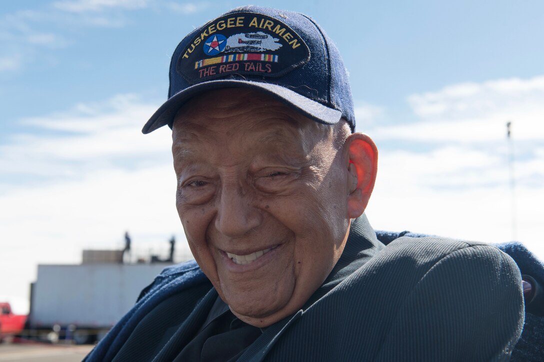 A veteran wearing a Tuskegee Airmen baseball hat smiles for a photo.
