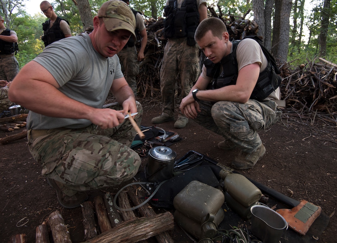 Airman carves spoon while other airman watches