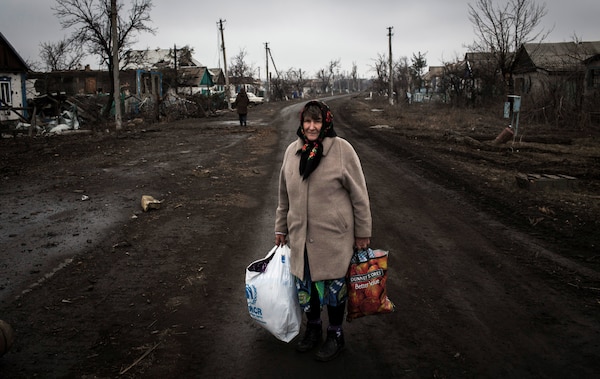 Eastern Ukrainian woman, one of over 1 million internally displaced persons due to conflict, has just returned from her destroyed home holding all her possessions, on main street in Nikishino Village, March 1, 2015 (© UNHCR/Andrew McConnell)