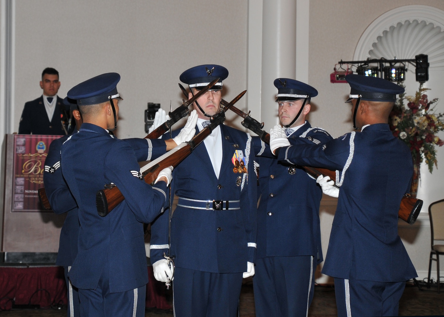 Five members of the Air Force Honor Guard Drill Team hold weapons at the ready to perform precision drill exercises to entertain the audience during the 2nd Annual DLA Ball.
