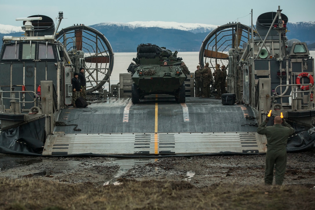 U.S. Marines and Sailors offload a light armored vehicle from a landing craft, air cushion on Alvund Beach, Norway, during an amphibious landing in support of Trident Juncture 2018, Oct. 30, 2018. Trident Juncture provides a unique environment for the Marines and Sailors to rehearse their amphibious capabilities. The LCACs originated from USS New York (LPD 21) and showcased the ability of the Iwo Jima Amphibious Ready Group and the 24th Marine Expeditionary Unit to rapidly project combat power ashore. The vehicles and Marines are with 2nd Light Armored Reconnaissance Battalion, 24th MEU. (U.S. Marine Corps photo by Lance Cpl. Margaret Gale)