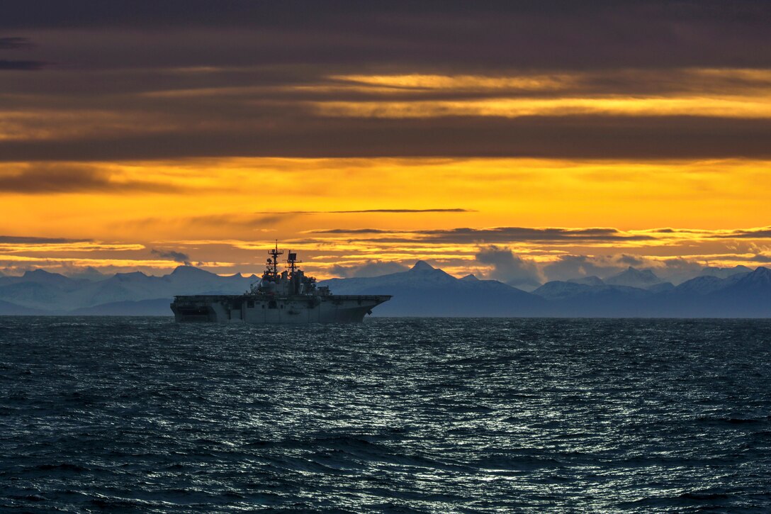 A ship travels below a dramatic orange-streaked sky.