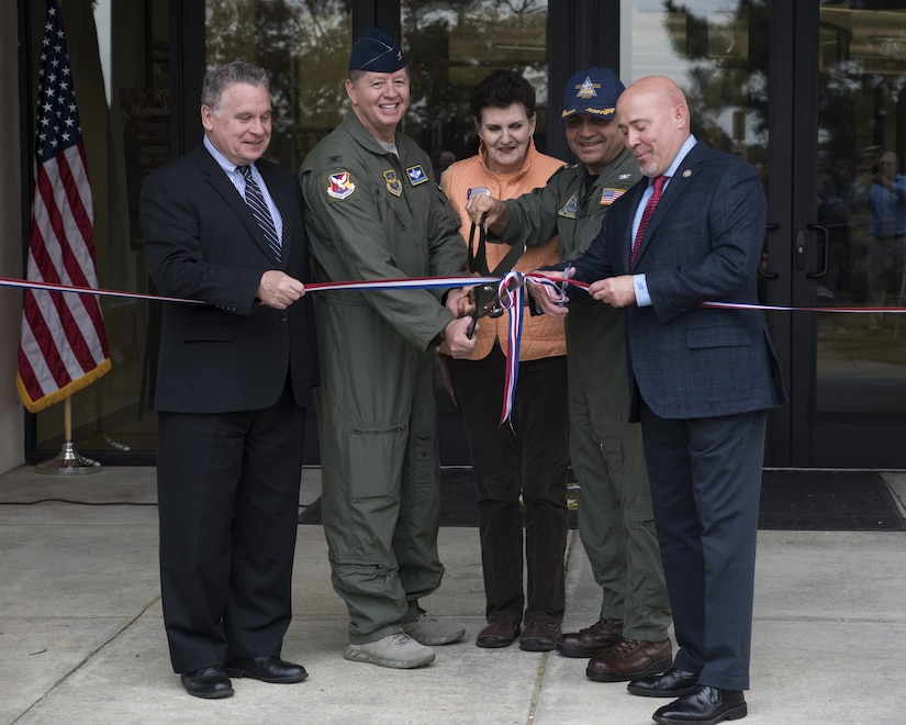 U.S. Air Force Col. Neil Richardson, Joint Base McGuire-Dix-Lakehurst and 87th Air Base Wing commander, and U.S. Navy Capt. Muhammad Khan, Joint Base MDL deputy commander and Naval Support Activity Lakehurst commander, prepare to cut a ribbon with government officials during a ceremony marking the reopening of the Flight Deck on Joint Base MDL, New Jersey, Nov. 1, 2018. The Flight Deck, located on the Lakehurst side of the base, is open to all Joint Base community members and contains a theatre, game room, reading room, kitchen and the Information, Tickets and Travel Office. (U.S. Air Force photo by Airman 1st Class Ariel Owings)