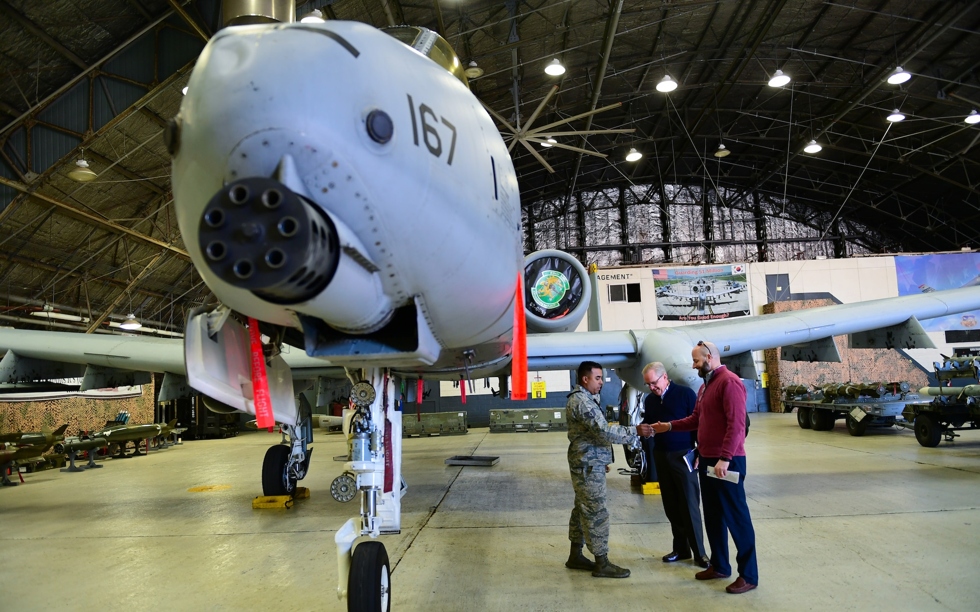 U.S. Air Force Tech. Sgt. Rigoberto Ayala, 51st Munitions Squadron armament backshop, gives a unit patch to Dave Giachetti and Craig Greene, House Armed Services Committee professional staff members, during a tour of Osan Air Base, Republic of Korea, Oct. 31, 2018.
