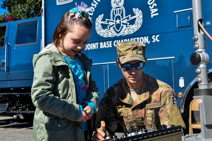 Senior Airman Michael Frook, 628th Civil Engineer Squadron explosive ordnance disposal technician, shows a youth center child how to control a robot during a mock deployment, Nov. 3, 2018, at Joint Base Charleston, S.C.