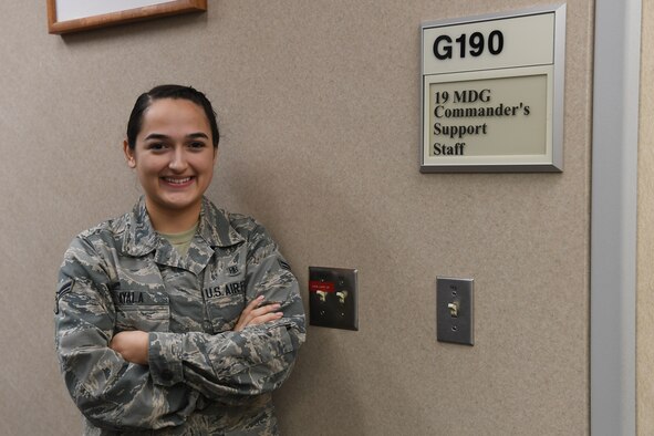 Woman stands besides wall.