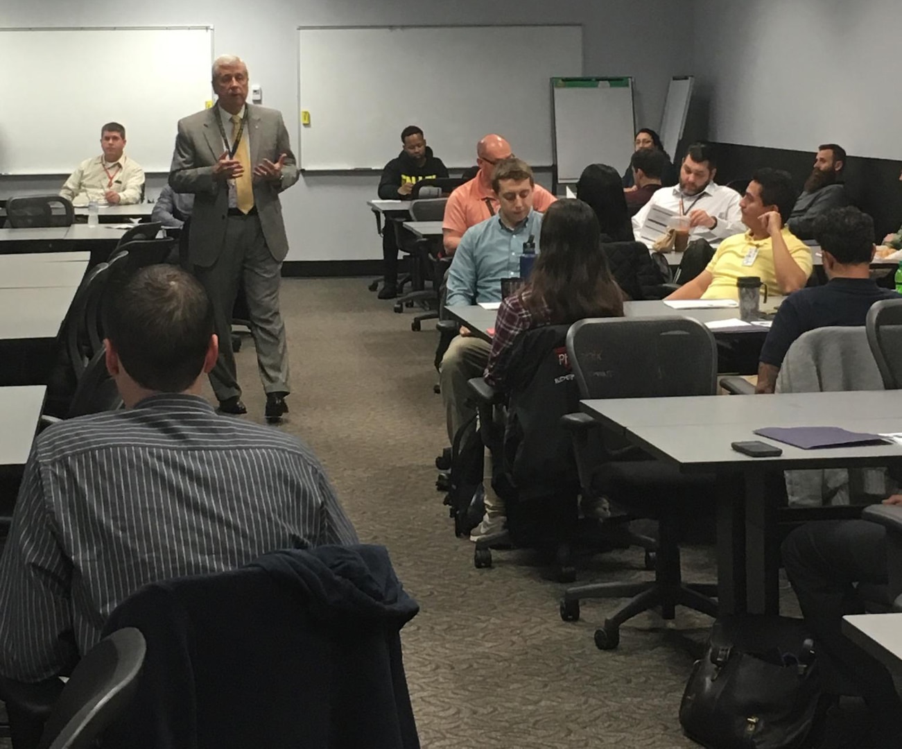 Defense Logistics Agency Land and Maritime Acquisition Executive Mark Brown speaks to a room of new associates.