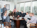 Eleven representatives sit around a table for a Technology Council meeting