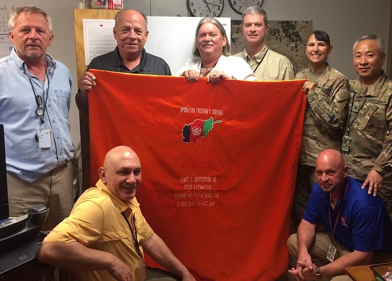 Jim Henderson proudly displays his Afghan Blanket that he received from his co-workers at the Afghanistan District Construction Division in Bagram Air Field. (Photo courtesy of USACE)