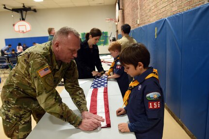 Sgt. David Lietz, public affairs sergeant with the 85th Support Command, shows a student how to fold an American Flag during the Lyon Elementary School Veteran’s Day observance in Glenview, Illinois, November 5, 2018.