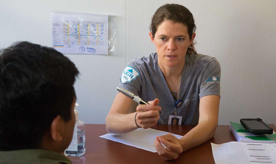 Lindsey Martin, a civilian nurse practitioner from Boston, and a member of the Global Disaster Response Team, Massachusetts General Hospital, discuss health concerns with a patient at one of two medical sites.
