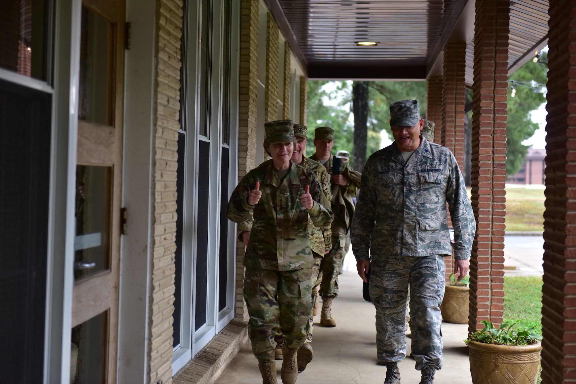 A woman wearing the operational camouflage patter uniform gives a thumbs up to a man wearing the airman battle uniform.