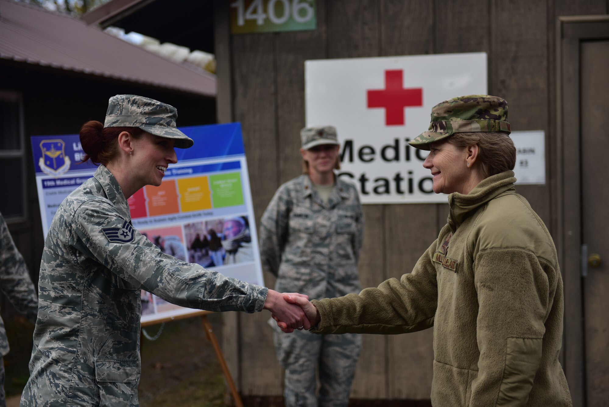 A woman in the operational camouflage patter uniform shakes hands with a woman wearing the airman battle uniform.