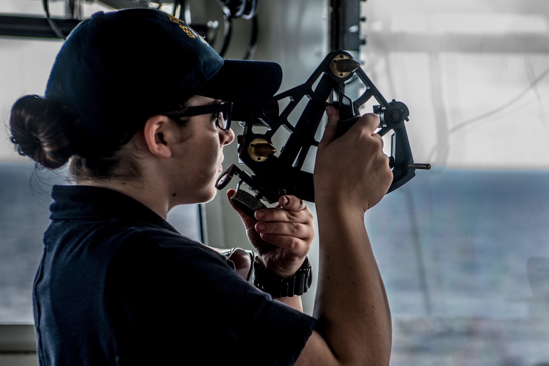 A seaman recruit  uses a stadimeter sextant looking across sea.