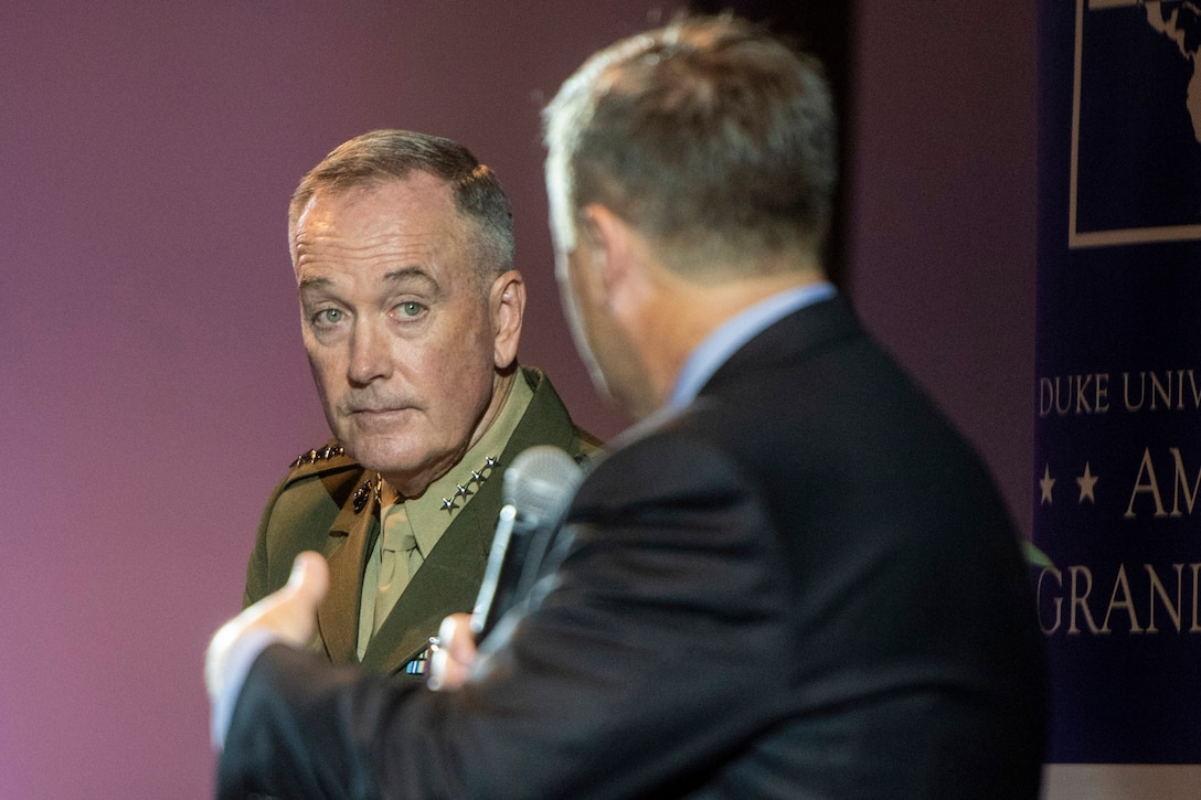 Marine Corps Gen. Joe Dunford listens as another man speaks to him.