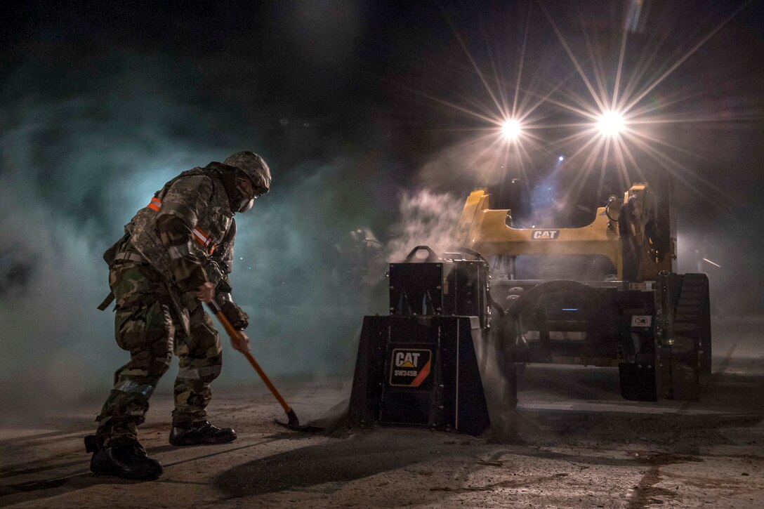 An airman shovels concrete.