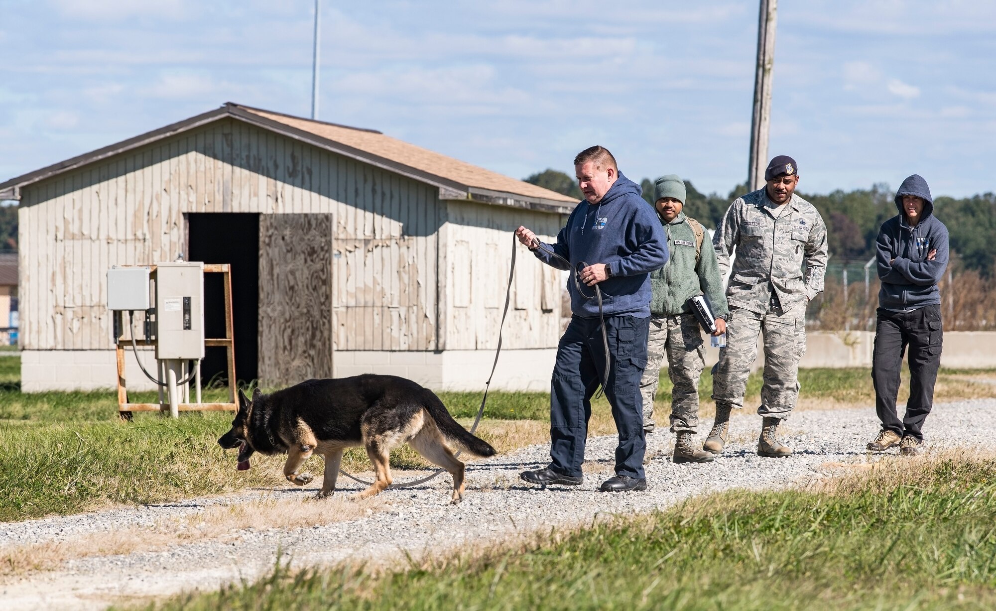Cpl. Dale Trotter, Worcester County, Md., Sheriff’s Department K-9 Unit handler, along with his partner, “Edo,” a nine-year-old German Shepherd explosive detection dog, search for hidden explosives Oct. 24, 2018, at Dover Air Force Base, Del. Standing in the background from left, Staff Sgt. Jared Brown, 436th Security Forces Squadron military working dog trainer, Tech. Sgt. Dominique Singleton, 436th SFS MWD kennel master, and Sgt. Katie Edgar, Worchester County, Maryland Sheriff’s Department K-9 Unit supervisor, watched Trotter work Edo as he searched for hidden explosives. (U.S. Air Force photo by Roland Balik)