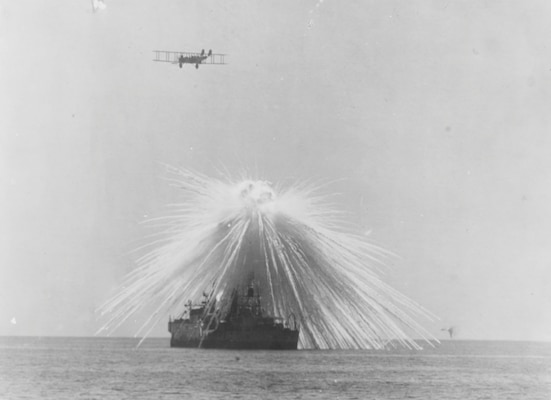 Ex–USS Alabama hit by white phosphorus bomb dropped by NBS-1 in bombing tests, as Army Martin twin-engine bomber flies overhead, Chesapeake Bay, September 23, 1921 (U.S. Naval History and Heritage Command)