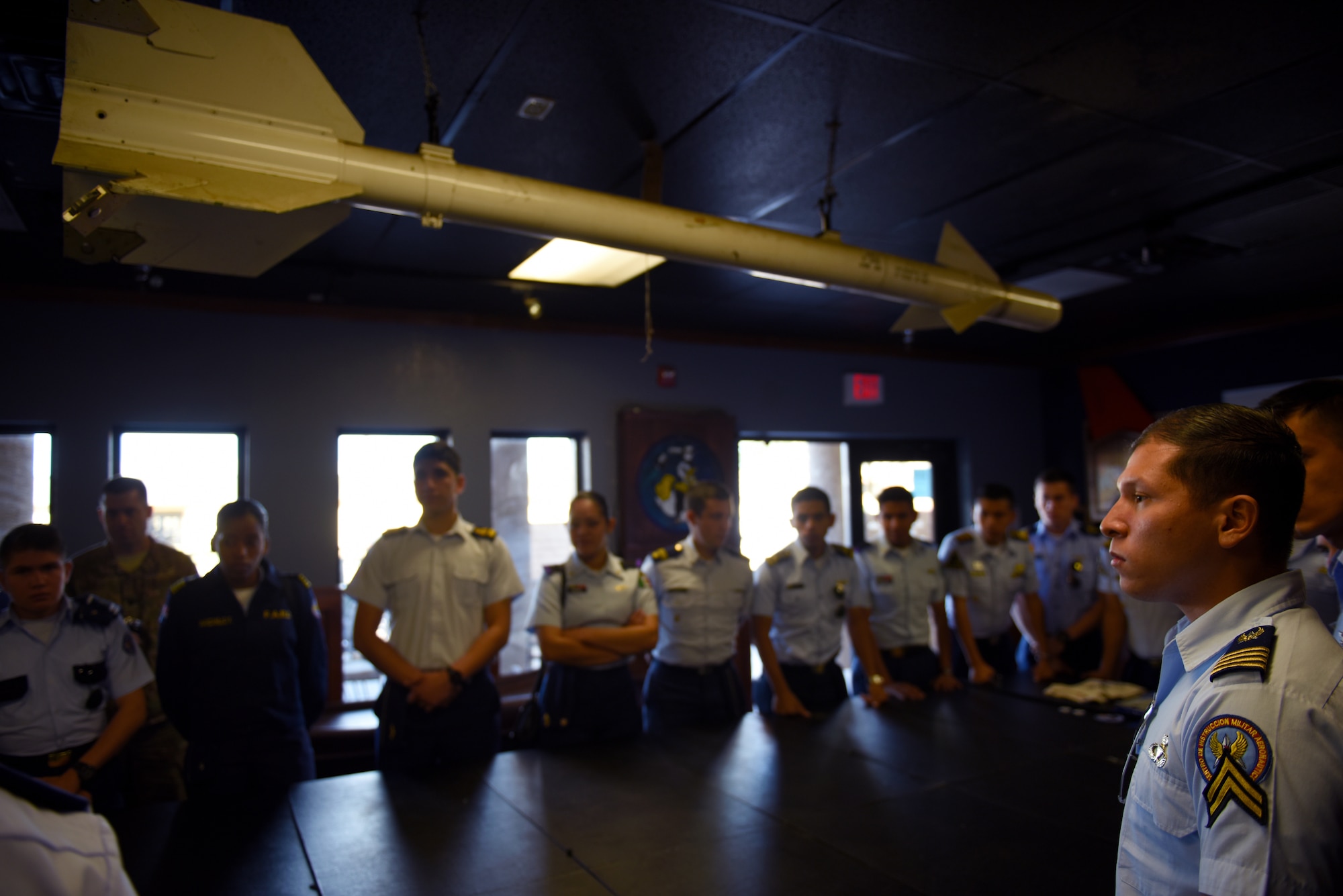 Distinguished cadets from different Latin American Air Force academies gather in the heritage room of the 309th Fighter Squadron to listen to U.S. fighter pilots speak about their experiences Oct. 31, 2018, at Luke Air Force Base, Ariz. Luke was one of several base visits the cadets made on their cross-country tour, a part of the Department of Defense Latin American Cadet Initiative. (U.S. Air Force photo by Senior Airman Ridge Shan)