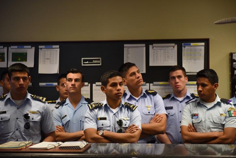 Distinguished cadets from different Latin American Air Force academies listen to U.S. fighter pilots speak about mission procedure at the 309th Fighter Squadron operations desk Oct. 31, 2018, at Luke Air Force Base, Ariz. The group was composed of the top two cadets from each of various Latin American air service academies from countries including Mexico, Brazil, and Colombia. (U.S. Air Force photo by Senior Airman Ridge Shan)