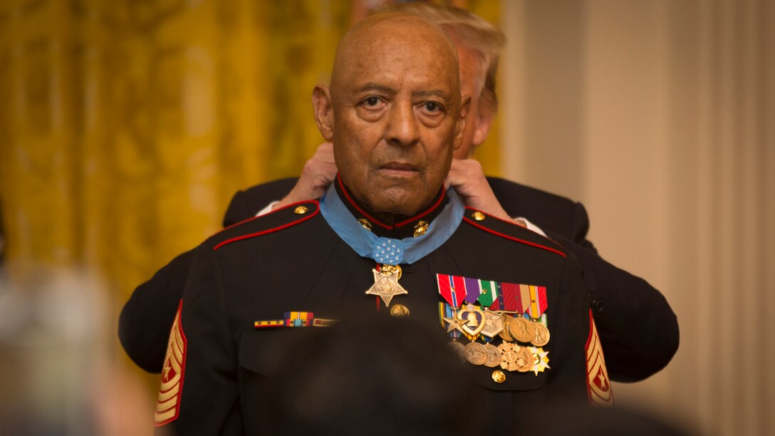 Marine Corps Sgt. Maj. John L. Canley is dressed in a custom Marine coat as he receives the Medal of Honor around his neck.