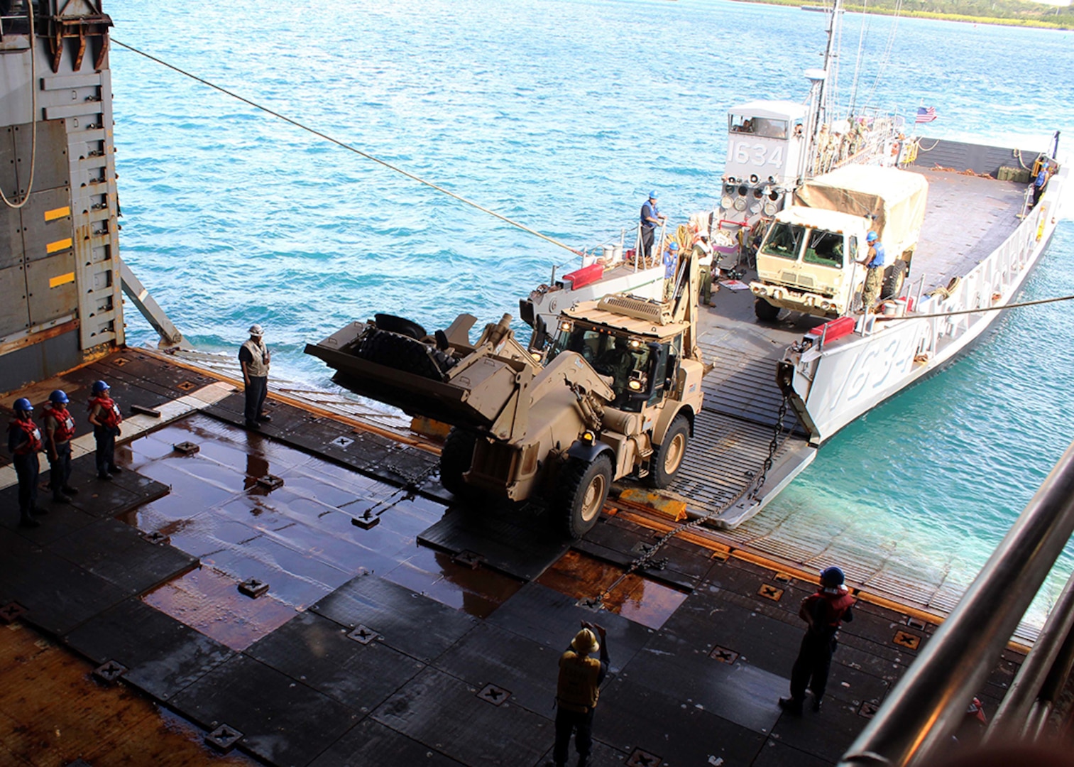 Heavy equipment vehicles from the 1224th Engineering Support Company, Guam Army National Guard, are loaded onto the well-deck of the Whidbey-Island class amphibious dock landing ship USS Ashland (LSD 48) via Navy Landing Craft, Utility (LCU) 1634, attached to Naval Beach Unit (NBU) 7 on Naval Base Guam.