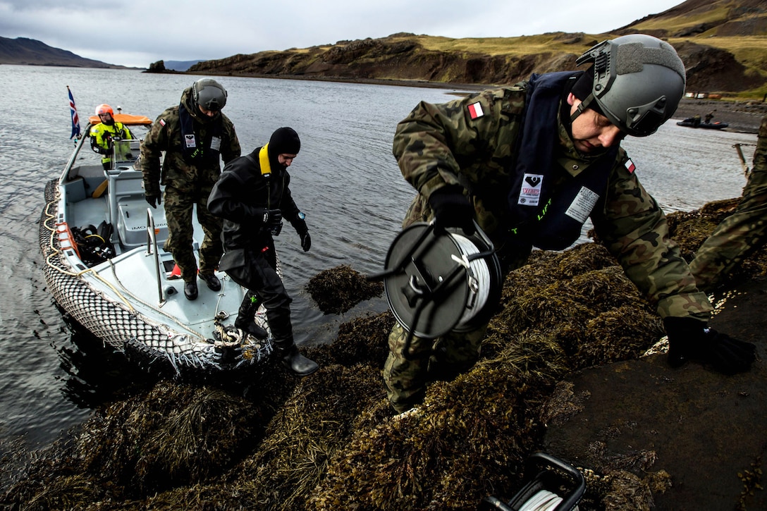 Three specialists come ashore from boat.