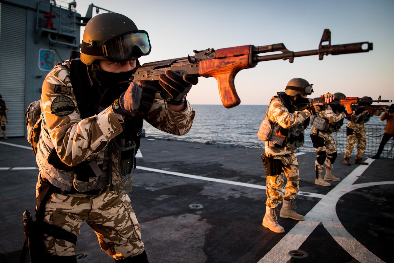 Romanian navy member points weapon during drill