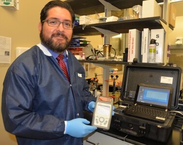 Dr. Luis Martinez, Naval Medical Research Unit San Antonio Craniofacial Health and Restorative Medicine Directorate research microbiologist, holds a handheld Raman spectrometer that is being utilized for a research project at the NAMRU-SA focused on the development of diagnostic platforms that can better identify bacterial pathogens in wounded service members. The handheld spectrometer is often used in the lab to further miniaturize and assess the field-readiness of the platforms under investigation as well as to establish detection limits and classification capabilities for bacteria recovered from biological specimens.