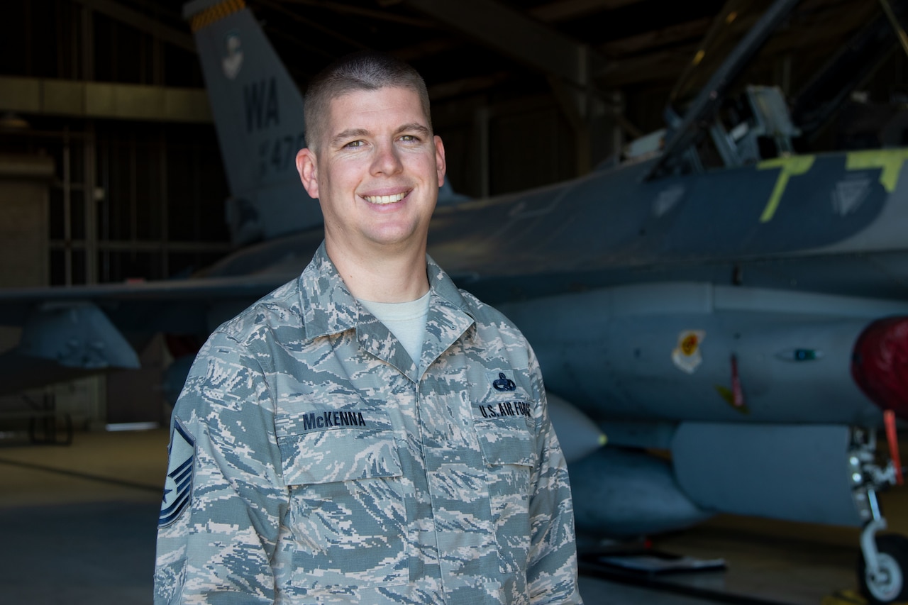 An airman stands in a hangar.