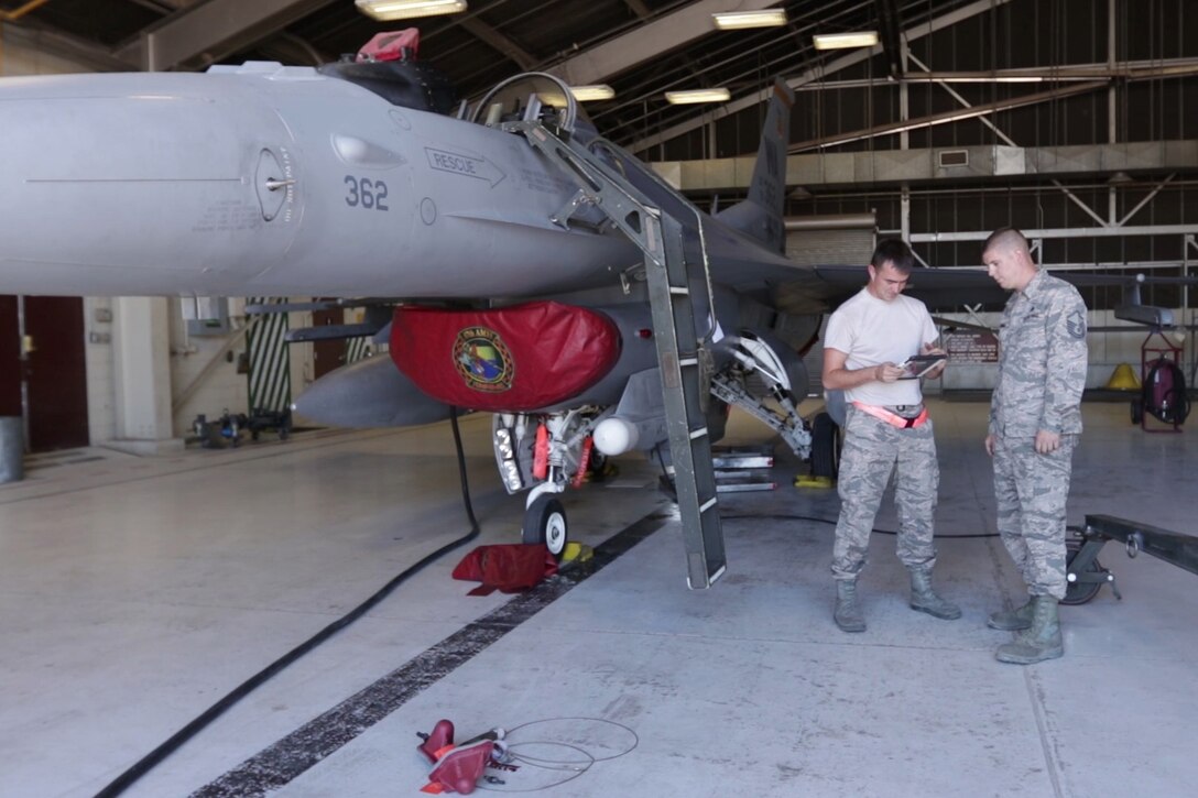 Two airmen review an electronic manual.