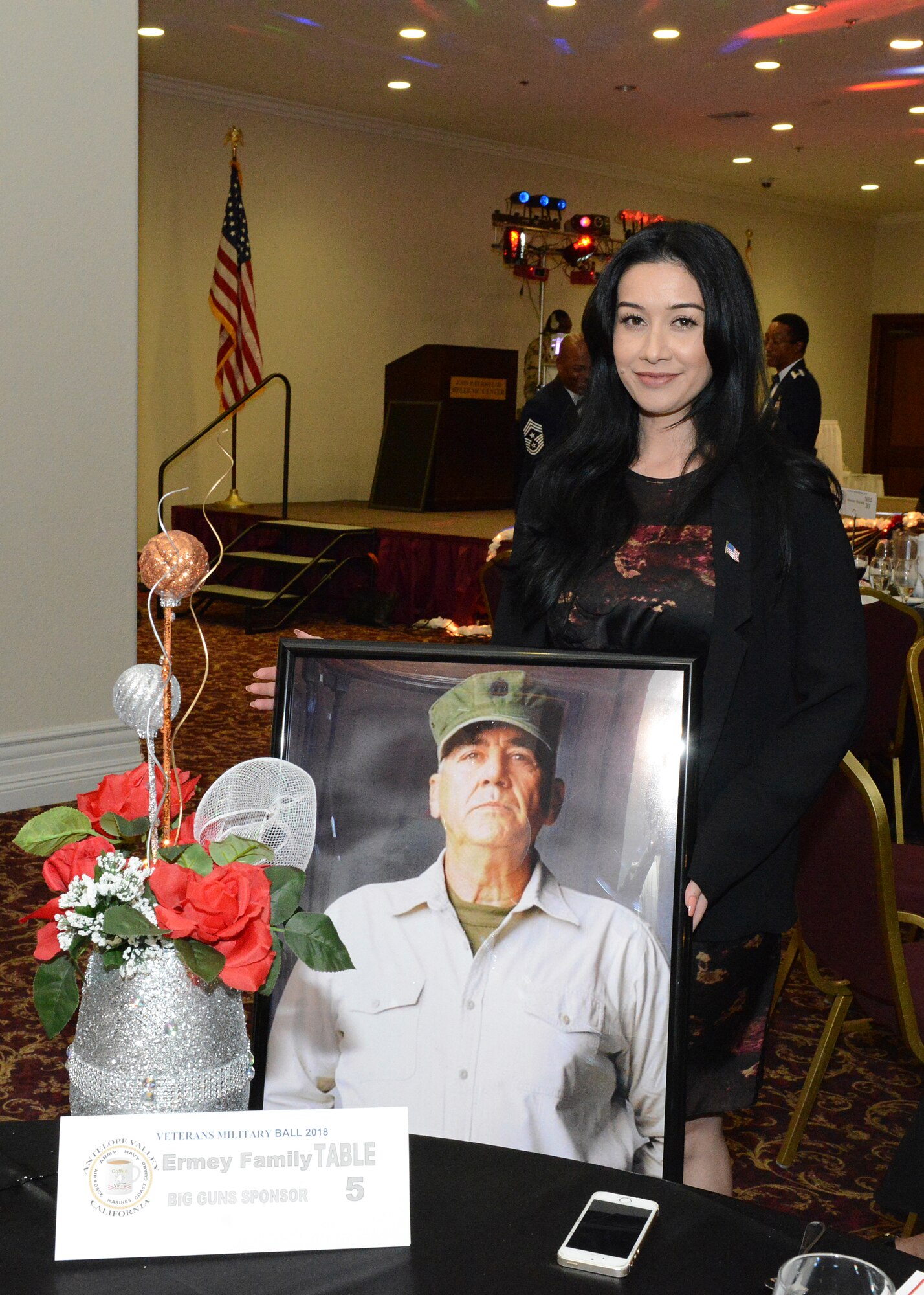 Betty Ermey, daughter of renowned actor and television personality R. Lee. Ermey, poses for a photo along with a picture of her late father at the Coffee4Vets Veterans Military Ball at the John P. Eliopulos Hellenic Center in Lancaster, California, Nov. 3. Betty Ermey spoke about her appreciation for military veterans at the event. (U.S. Air Force photo by Kenji Thuloweit)