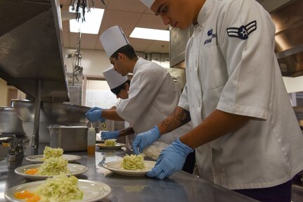 U.S. Air Force Airman 1st Class Jose Santana-Medina, 673d FSS food service specialist arranges salad placement for an orange tarragon salad being served during the grand opening lunch for JCI operated at the Gold Rush Inn. JCI is a new bi-monthly, two-week course, providing 10 food-service members from any military branch an opportunity to experience in-depth courses relating to the profession.