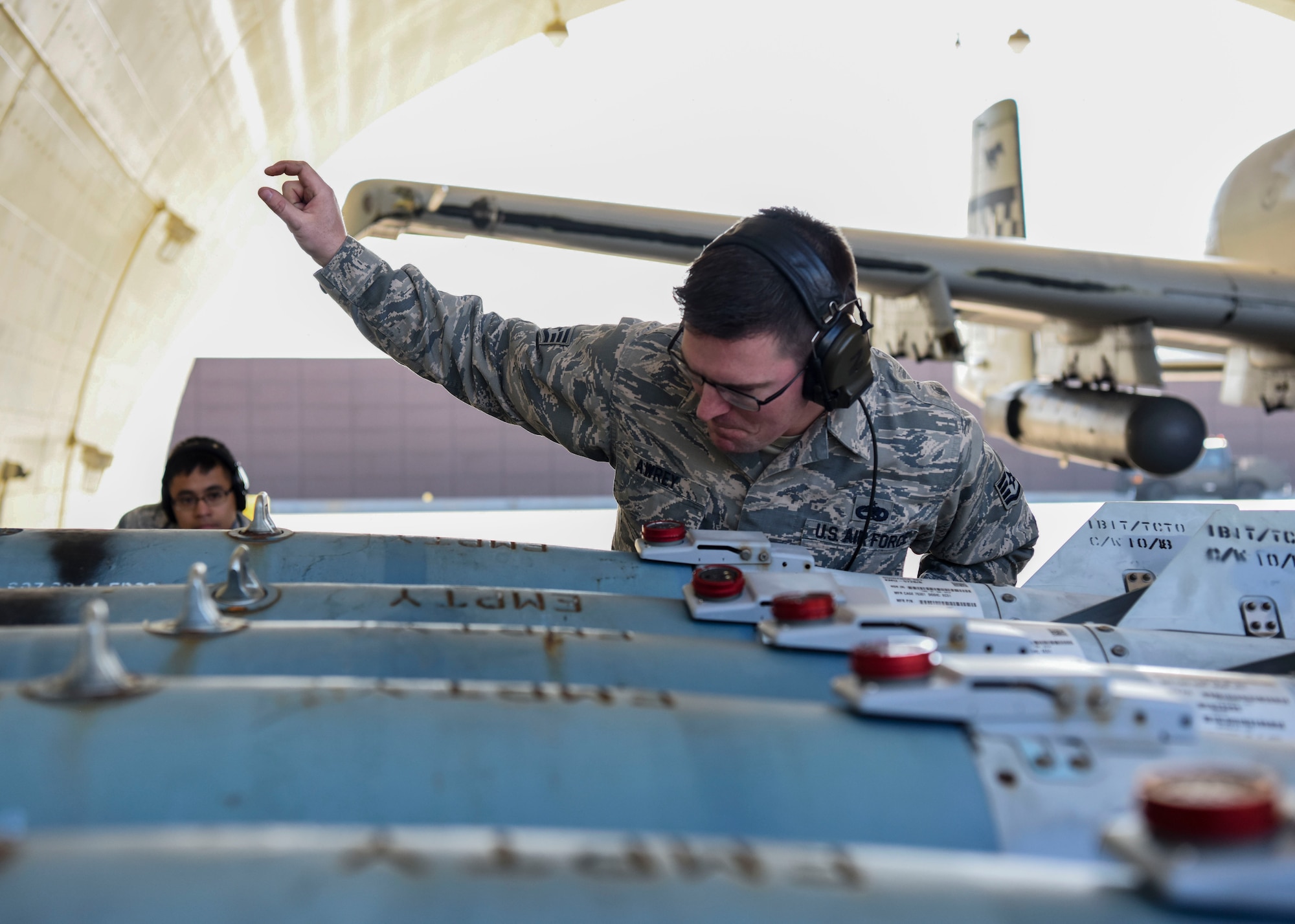 U.S. Air Force Staff Sgt. Nathaniel Awrey, 51st Maintenance Group standardized load crew team lead, signals U.S. Air Force Senior Airman Ryan Alquetra, 51st MXG standardized load crew team member, to lift munitions to load onto an aircraft at Osan Air Base, Republic of Korea, Nov. 2, 2018. The crew was able to load munitions onto the aircraft and send it off in under an hour by performing the loading operation while the aircraft engines were still running after hot refueling. (U.S. Air Force photo by Airman 1st Class Ilyana A. Escalona)