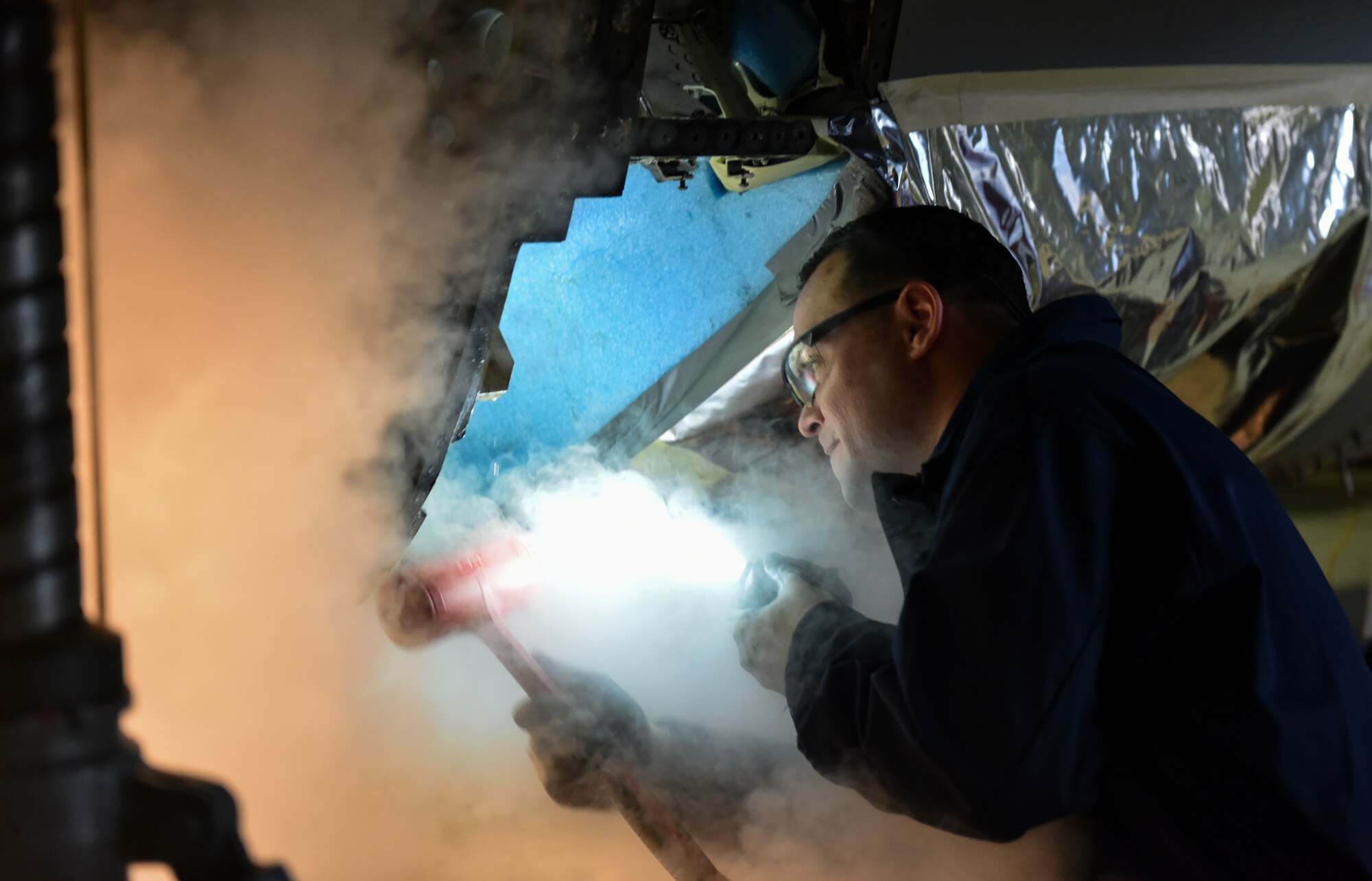 U.S. Air Force Staff Sgt. Joseph Gallegos, 309th Aircraft Maintenance Group depot structural maintenance specialist from Hill Air Force Base, Utah, attempts to remove the bulkhead of an F-16 Fighting Falcon with liquid nitrogen at Kunsan Air Base, Republic of Korea, Nov. 8, 2018. Replacement parts are being installed to change dated parts on F-16s in the Wolf Pack fleet and to sharpen the 8 Fighter Wing’s lethality. (U.S. Air Force photo by Senior Airman Stefan Alvarez)