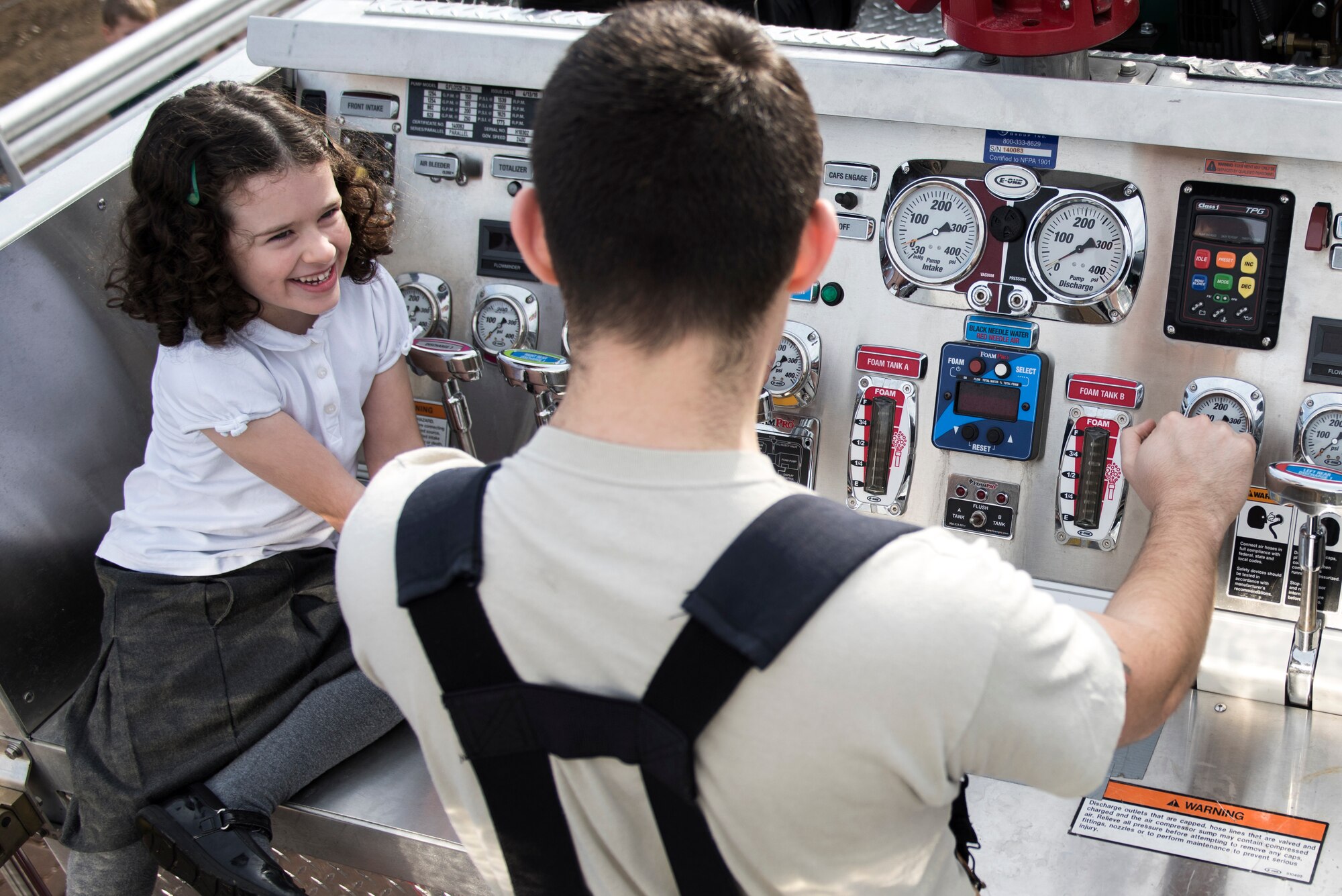 A student learns about the water controls of a fire engine from a 48th Civil Engineer Squadron firefighter during an Everyday Heroes event at Pines Primary School in Red Lodge, England, Nov. 5. During the hour-and-a-half showcase, the firefighters provided the students with interactive demonstrations with life-saving equipment, such as the protective gear and firefighting gear, and enjoyed a full tour of a fire engine. (U.S. Air Force Photo/ Senior Airman Malcolm Mayfield)