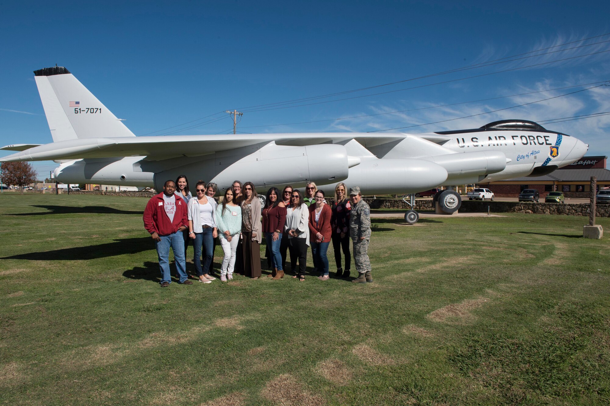 Military spouses from the 97th Air Mobility Wing and members of the 97th Force Support Squadron Airman and Family Readiness Center pose in front of a static B-47 Stratojet display during the Heartlink Spouse Orientation