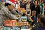 Alaska Air National Guard Staff Sgt. Vanessa Peterson hands out snacks to children in Emmonak during Operation Santa Claus on Nov. 1, 2018. Operation Santa Claus is an Alaska National Guard annual community outreach program that provides Christmas gifts, books, backpacks filled with school supplies, fresh fruit, and sundaes to youngsters in rural communities.