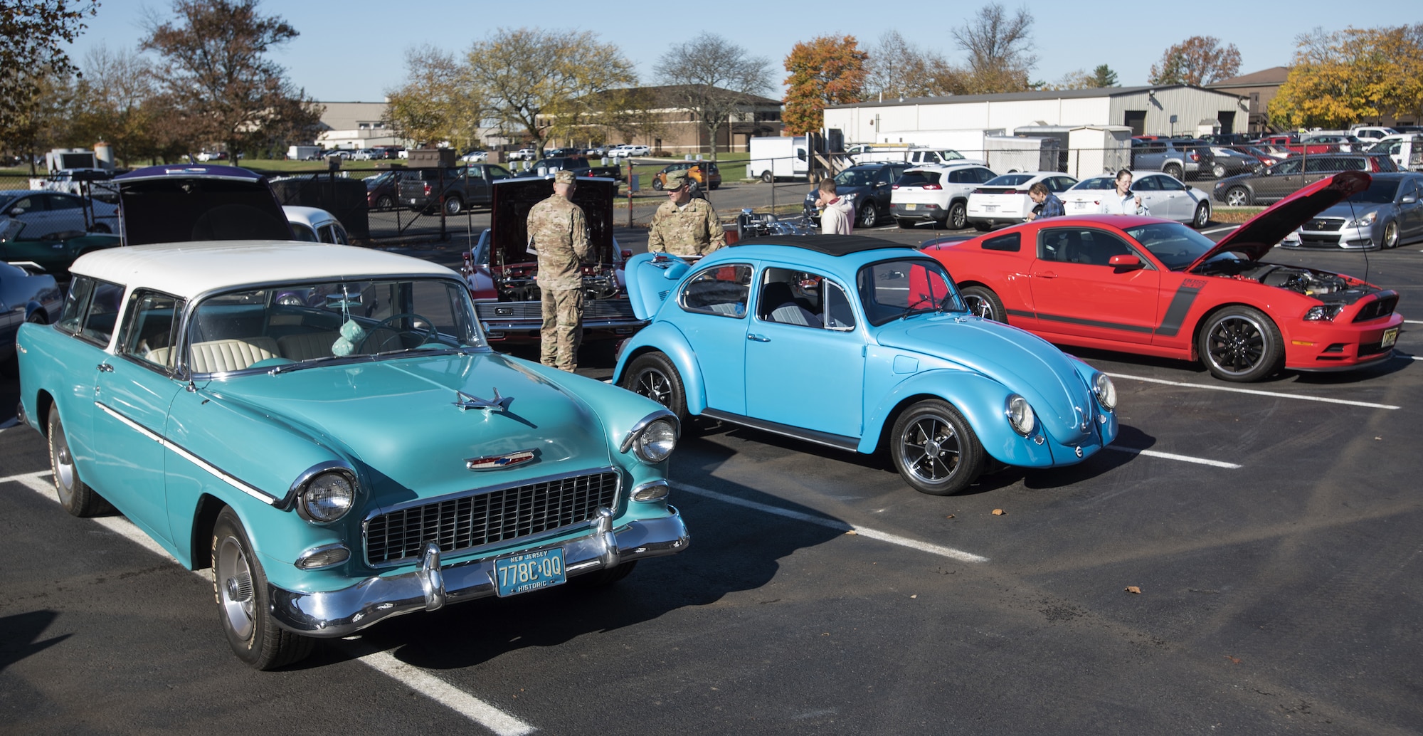 Joint Base McGuire-Dix-Lakehurst community members look at cars displayed during a ceremony marking the reopening of the Auto Hobby Shop on Joint Base MDL, New Jersey, Nov. 7, 2018. Cars were showcased to show the many features the shop has to offer. (U.S. Air Force photo by Airman 1st Class Ariel Owings)