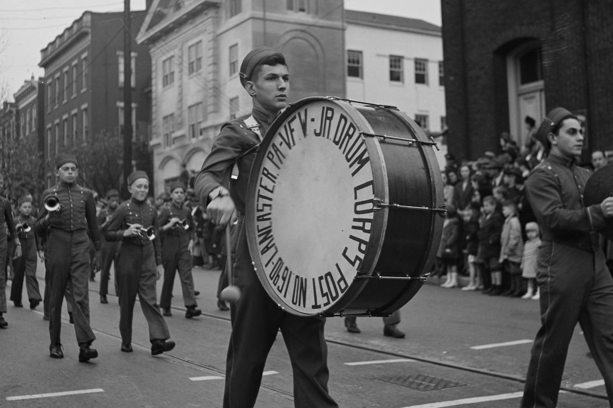 A drummer walks in a parade.