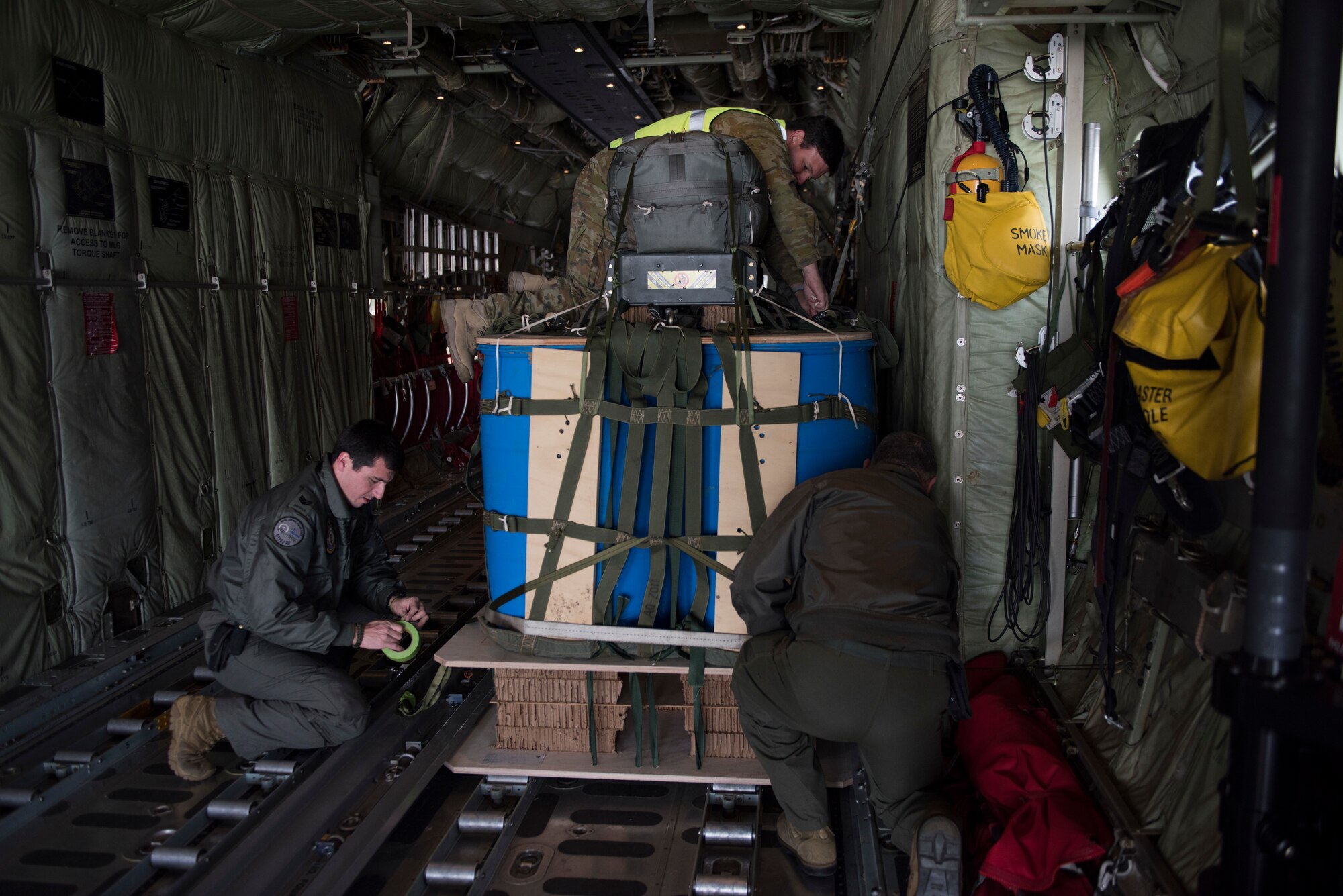 Image of members of the Australian military work together to trap down cargo on a C-130J Super Hercules before a flight Nov. 1, 2018, at Mountain Home Air Force Base, Idaho. One reason the RAAF chose to come to Mountain Home AFB to train is for the terrain, which is very different from Australia.(U.S. Air Force photo by Senior Airman Alaysia Berry)