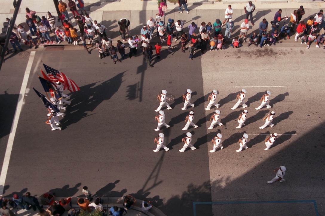 A formation of troops, shown from overhead, march in a parade.
