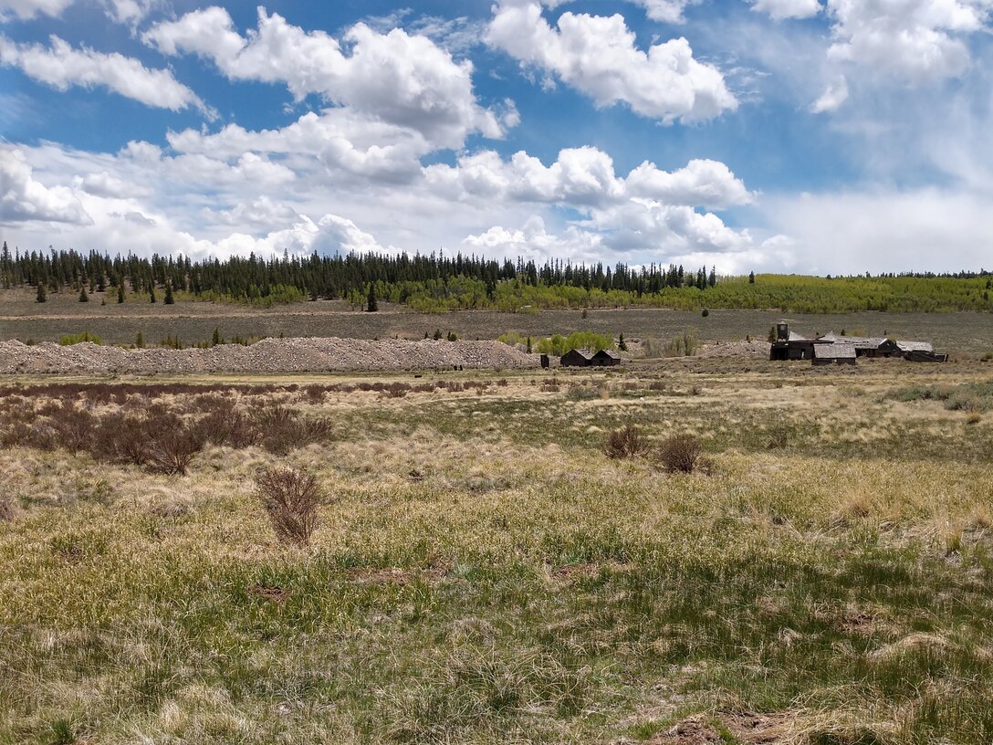 A spring-fed wetland complex associated with Corske Creek (foreground) with historic placer mine tailings, and the remains of the historic Hallenbeck Ranch. (background).